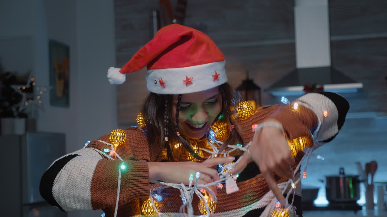 mujer festiva con sombrero de santa tratando de desenredar las luces