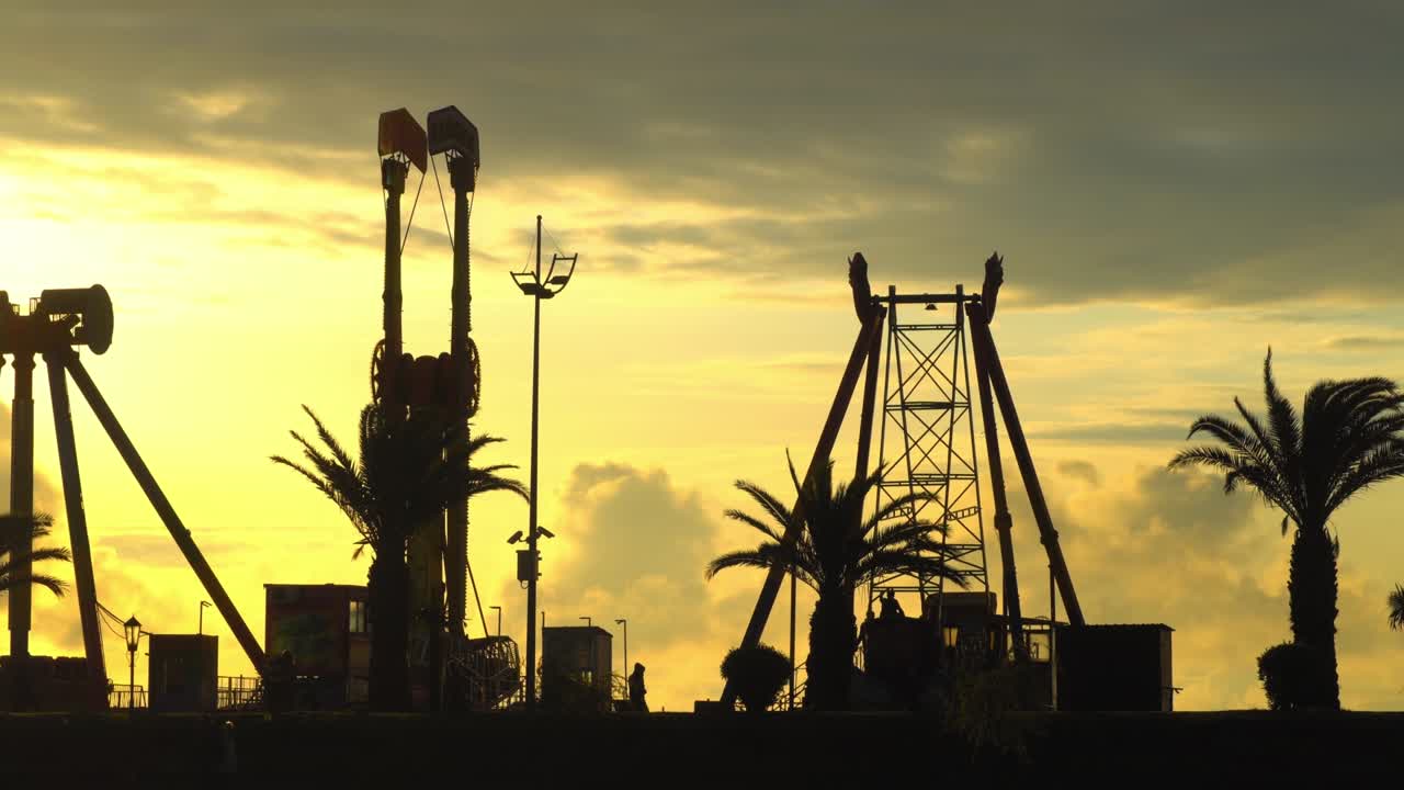 Back light of sunset or dawn. Silhouettes of amusement park with oral sky.