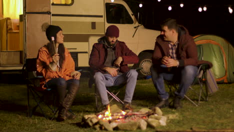 group for friends singing together around camp fire