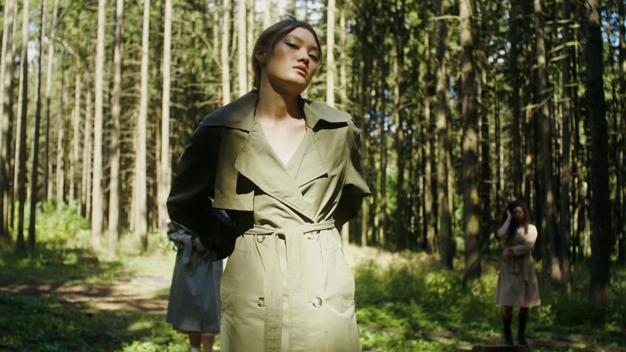 Women wearing trench coats in a forest