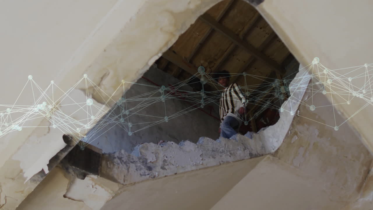 man leaning through jagged ceiling opening in construction, showing digital node network technology