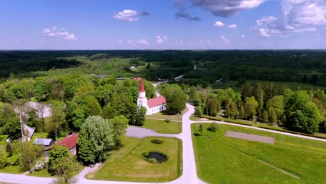 Skujene,-Latvia,-Europe---A-Picturesque-Sight-of-the-Evangelical-Lutheran-Church-in-Skujene-Village---Aerial-Pullback-Shot