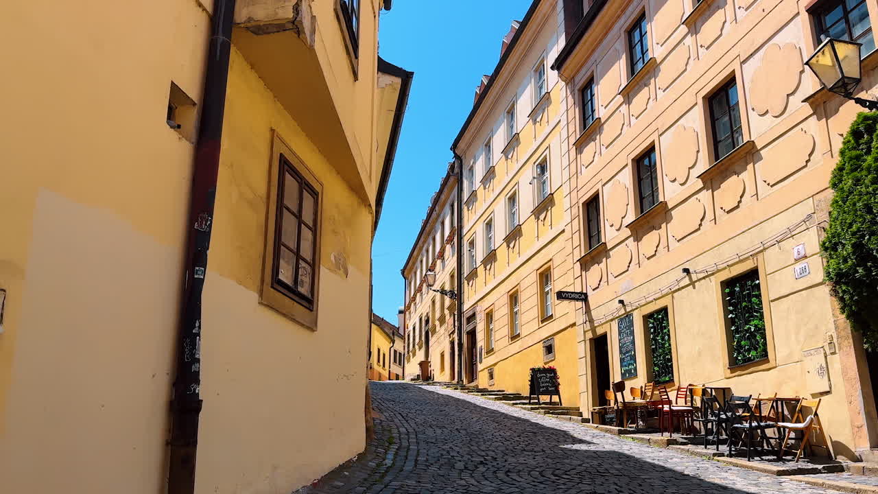 Bratislava, Slovakia, 2 June 2025: Walking by the old paved street along the stunning buildings' facades. Historical part of Bratislava, Slovakia on sunny day