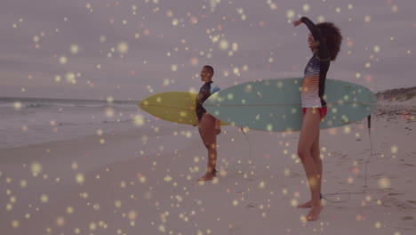 female surfers holding surfboards raising arms beach sports animation showing floating golden bokeh