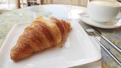 delicious croissant and cappuccino for breakfast at a cozy cafe