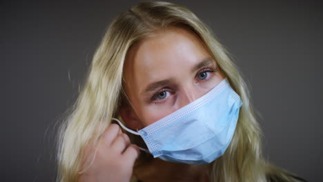 smiling blonde woman removes face mask pan