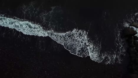 crashing foamy ocean waves create stunning textures and intricate patterns on black sand beach in ponta do sol, madeira island, portugal, capturing the beauty of nature's artistry, top down drone shot