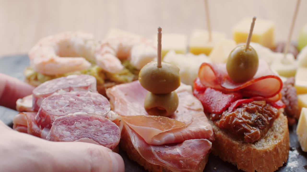 Hand holding tapas platter with various appetizers