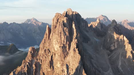 close drone view as first rays of sunrise hit peaks of cadini di misurina, italy