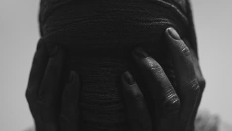 a mummified woman against the bright background in keeps her hands on her face the powerful pose full of despair