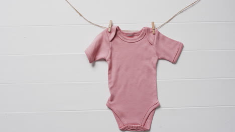 video de un bebé rosa que crece colgado de la ropa mendiga en línea con espacio de copia en fondo blanco