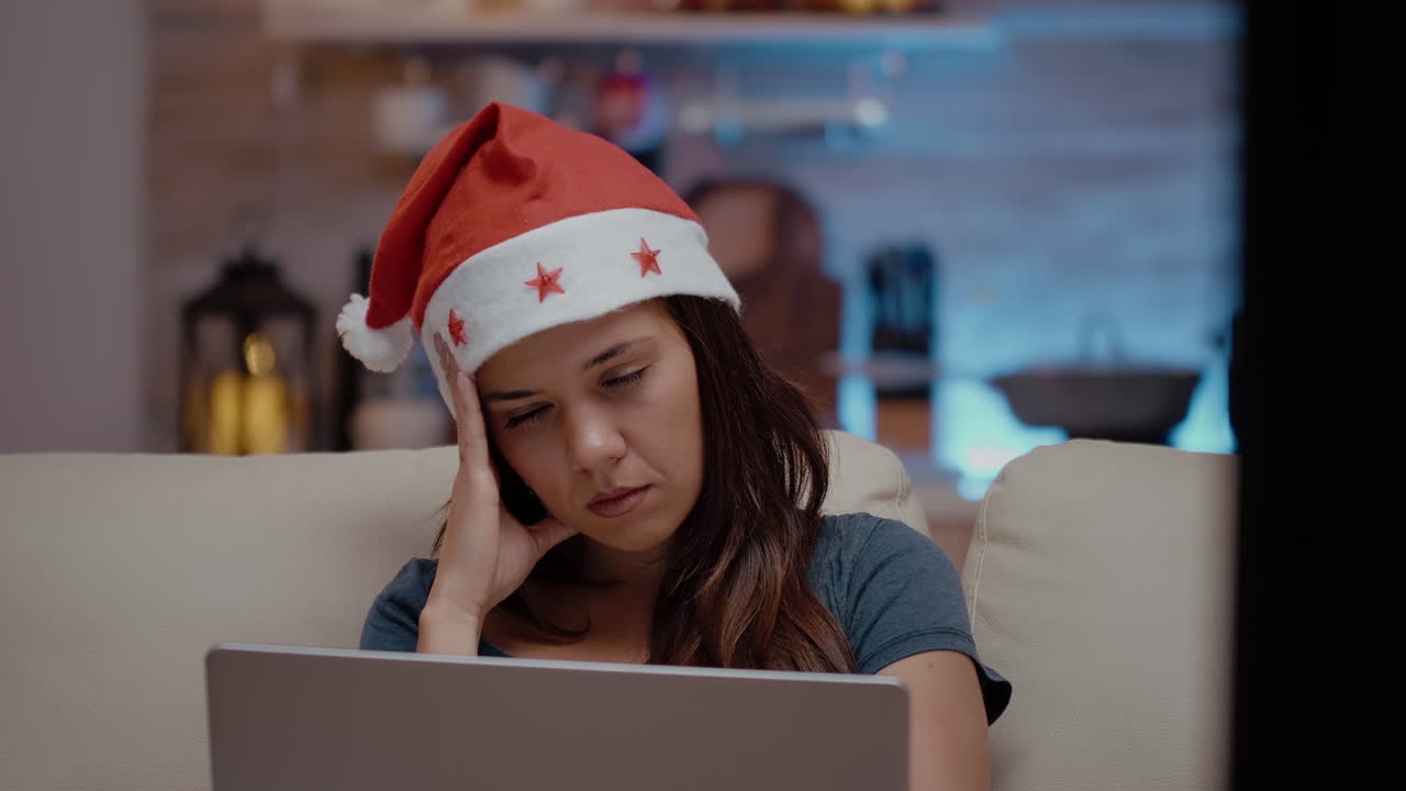 Close up of sleepy adult looking at laptop on christmas eve