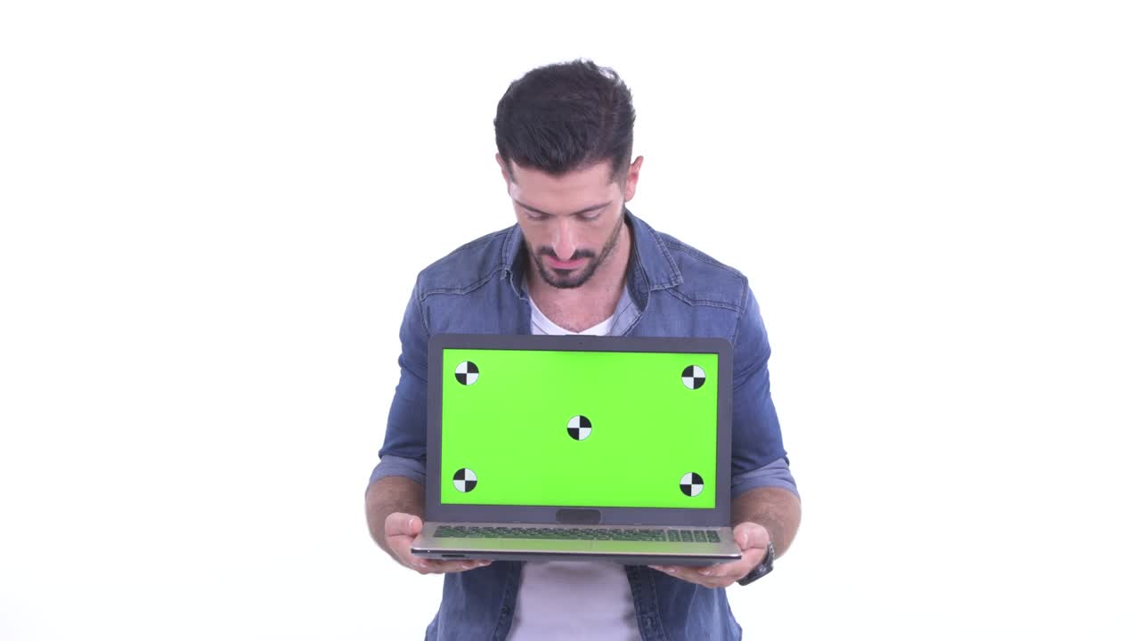 fotografía de estudio de un hombre guapo mostrando una computadora portátil con pantalla cromada mientras habla contra un fondo blanco
