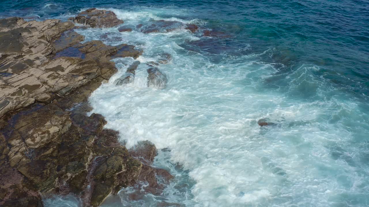 toma de drones de olas rebotando en las rocas en la playa