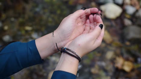 point of view shot of gothic female hands scooping water from a river in the forest