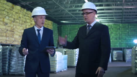 two business professionals in hard hats inspecting a large warehouse