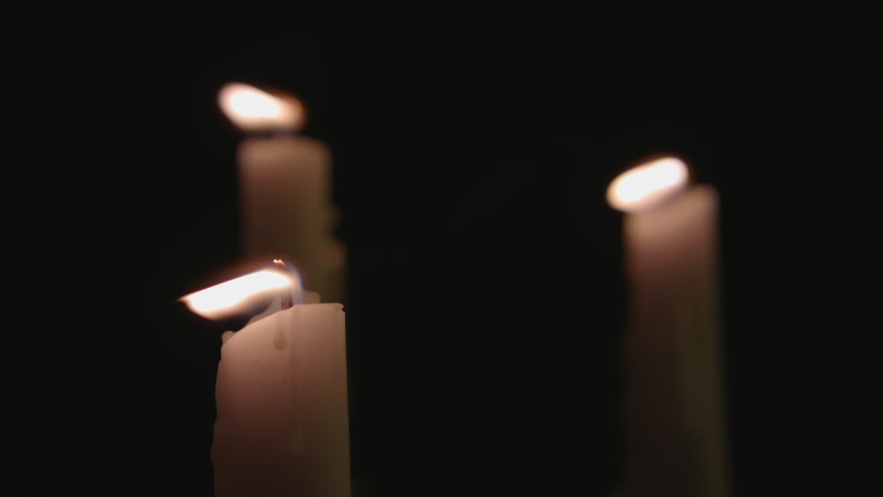 Quattro candele bianche accese e una rapida panoramica su di esse.