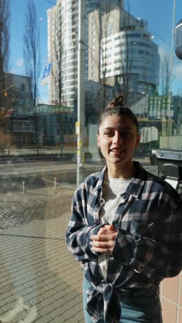 joven sonriendo frente a la ventana de la ciudad