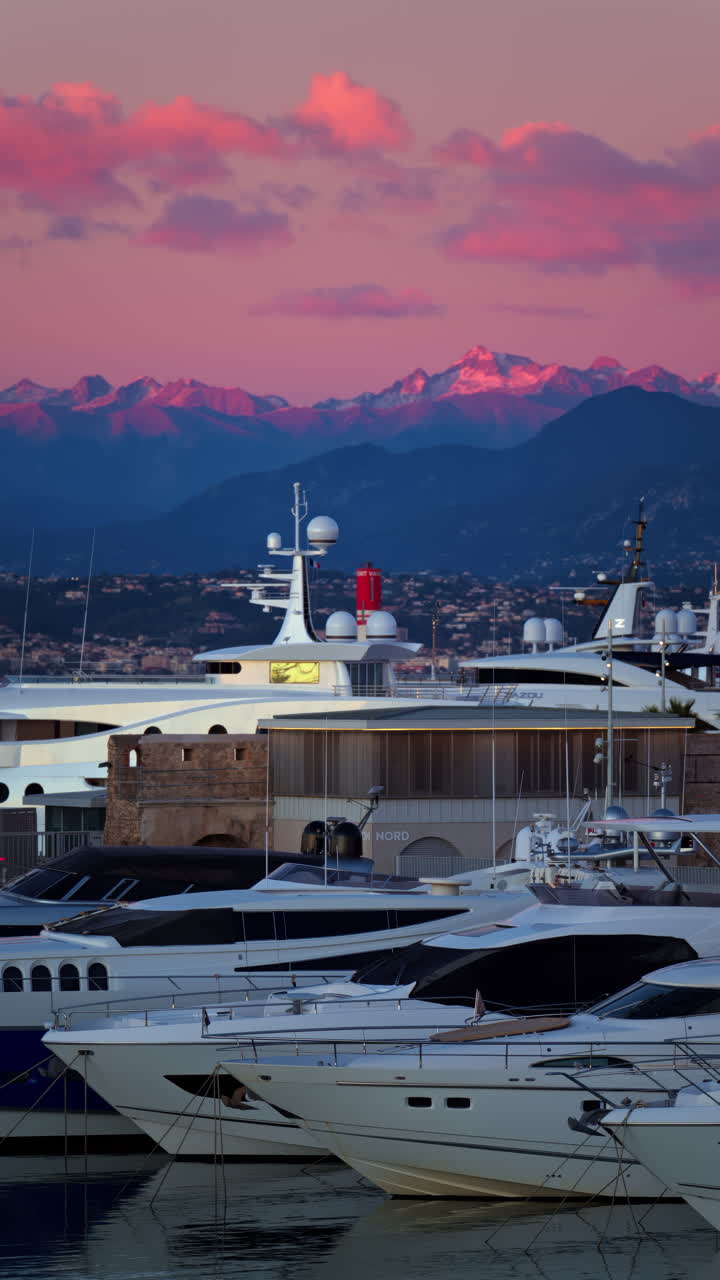Multiple white boats docked in the Port Vauban, Antibes, France with the mountains on the background at sunset. Vertical