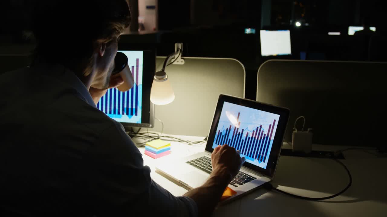 vista trasera de un joven ejecutivo caucásico trabajando en una computadora portátil en un escritorio en una oficina moderna 4k