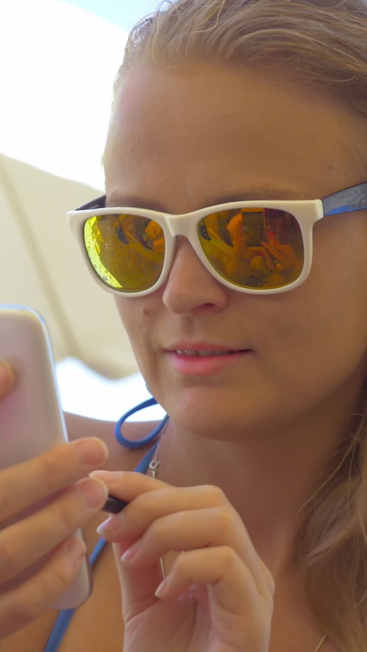 Woman at the Beach with Sunglasses Using Her Phone