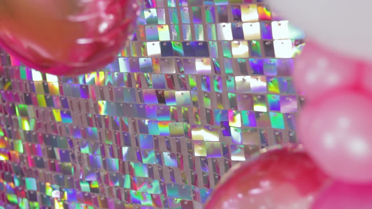 un telón de fondo de pañuelos iridescentes brillantes con globos rosados que crean una atmósfera festiva y vibrante