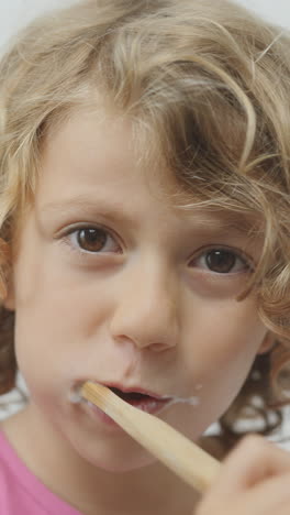 una niña pequeña cepillándose los dientes en vertical