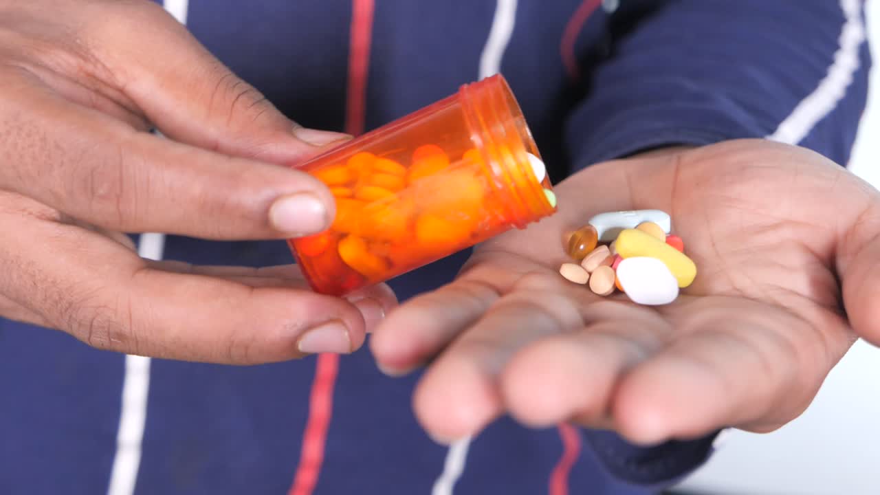 persona vertiendo pastillas de una botella en su mano