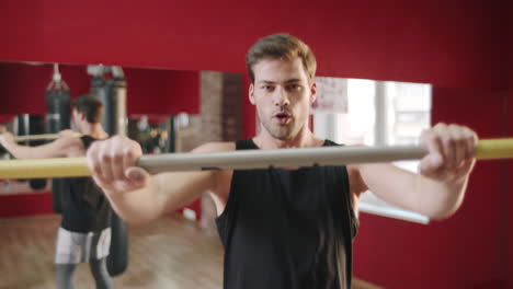 young man jumping with crossbar at fitness training in gym club