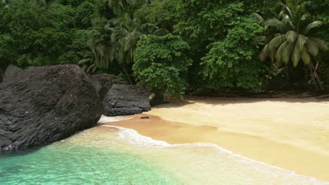 drone flyover turquoise colored waters from the beach shore in principe island, africa