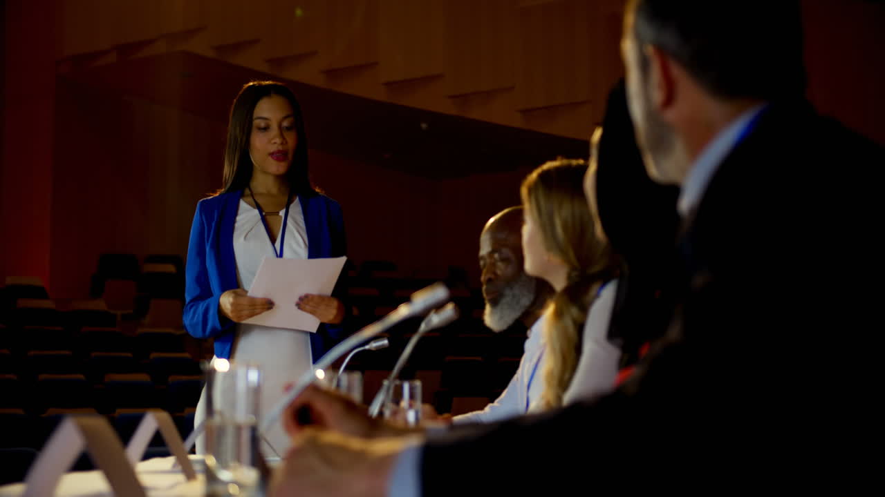 Young Caucasian businesswoman talking with colleagues on stage in auditorium 4k