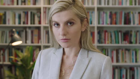 portrait of attractive blonde business woman looking serious at camera wearing stylish suit in library office background