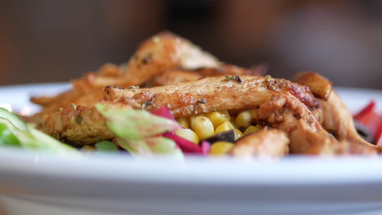 primer plano de una ensalada de pollo con maíz, lechuga y pimienta roja