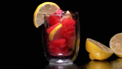 Glass-filled-with-watermelon-cubes-and-lemon-slices-being-sprayed-with-water