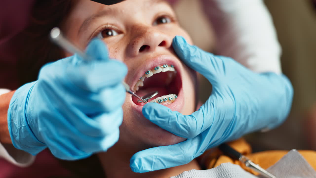 A young woman with braces having her teeth checked by a dentist