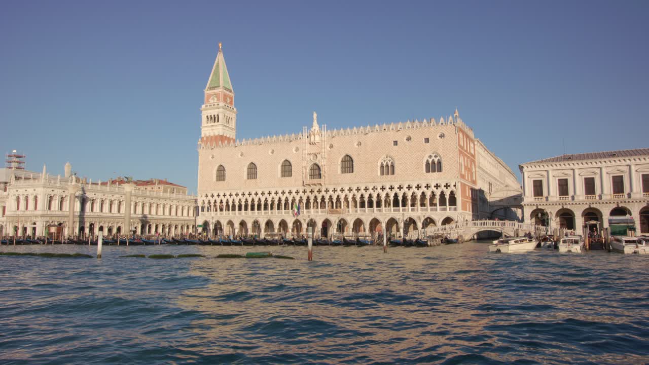 Palazzo Ducale e Campanile di San Marco a Venezia visti dall'acqua con onde leggere e architettura storica che creano un'iconica scena cittadina sul lungomare dalla prospettiva di una barca