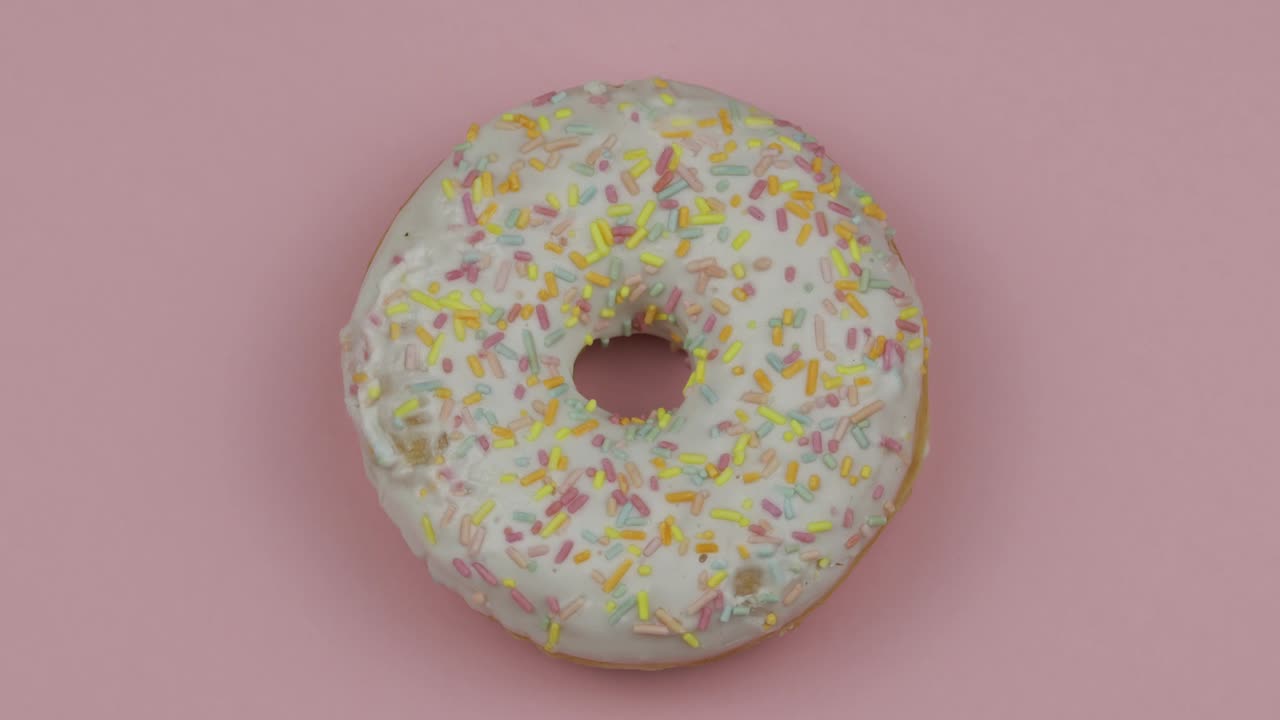 Søt smultring roterende på rosa bakgrunn. Sett ovenfra. Velsmakende, fersk smultring med strøssel.