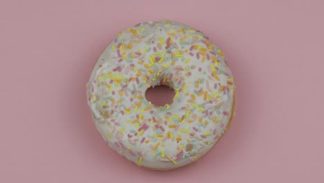 sweet donut rotating on pink background. top view. tasty, fresh sprinkled donut