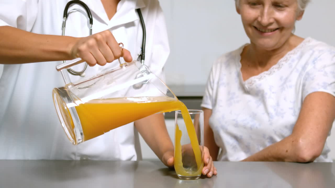 Home help pouring juice for patient in kitchen | Premium Stock Video ...
