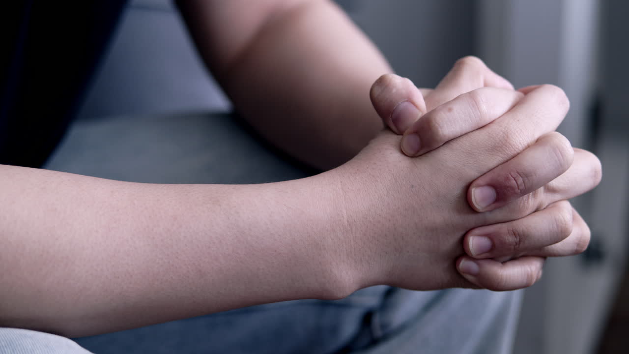 Close up of an Asian man's hands clasped tightly as a psychological impact of excessive anxiety. Mood of sadness, depression, and disappointment.