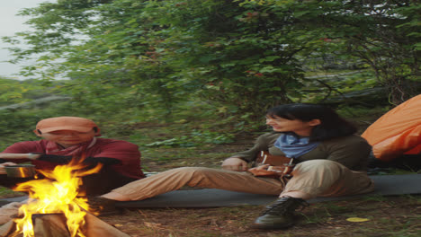 girlfriends playing guitar near campfire