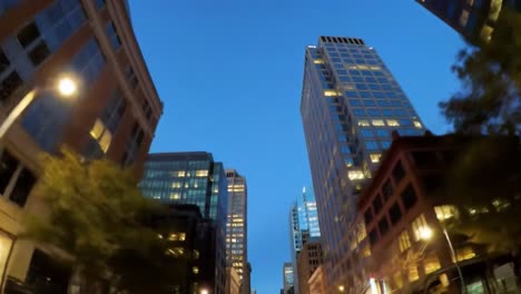 an evening stroll through a bustling city, showcasing towering buildings against a deep blue sky. the warm glow of lights creates an inviting atmosphere as night falls.