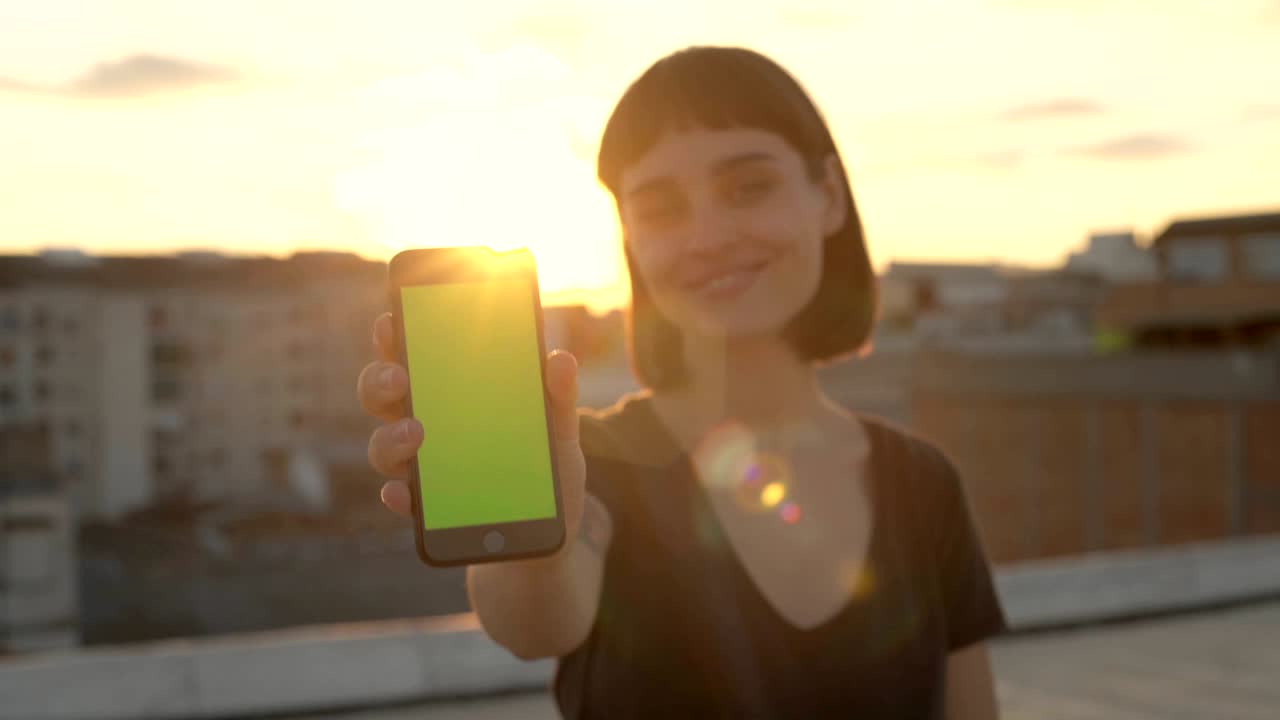 atractiva morena con gadget en el techo al atardecer