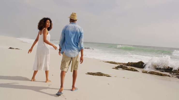 Vista posteriore di coppia afroamericana che cammina sulla spiaggia 4k