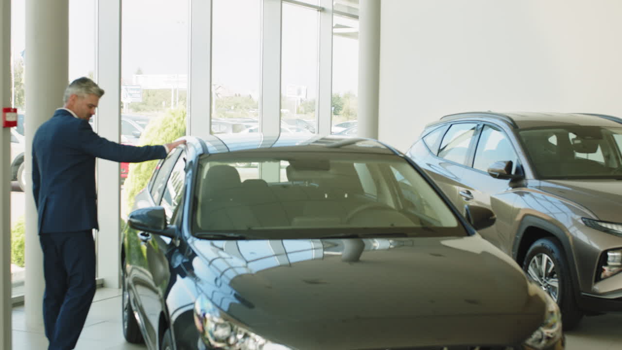 한 남자 가 자동차 대리점 에서 차 를 확인 하고 있다