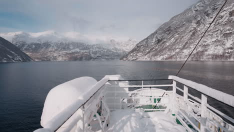 Vídeo-En-Primera-Persona-De-Un-Viaje-En-Ferry-A-Través-Del-Fiordo-De-Geiranger-En-Invierno,-Que-Presenta-Impresionantes-Vistas-De-Montañas-Cubiertas-De-Nieve,-Un-Cielo-Brillante-Y-Reflejos-En-El-Fiordo.