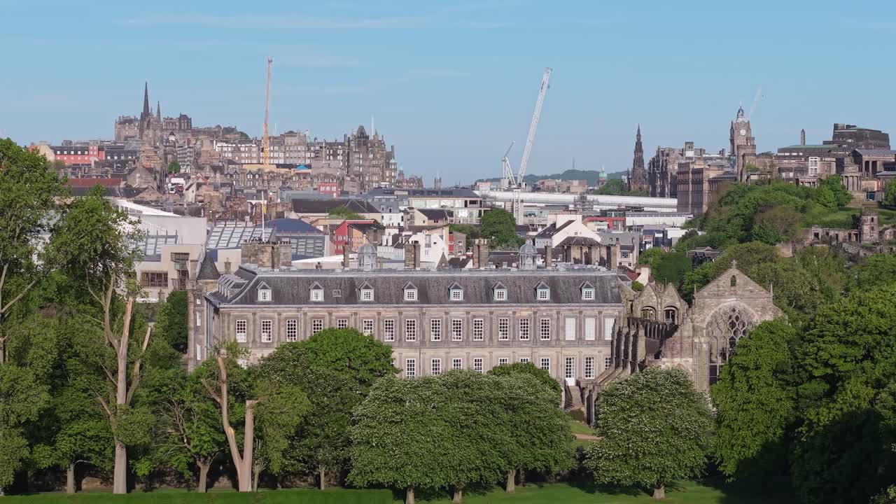 Drone footage from the lush gardens of Holyroodhouse Palace gradually revealing the stunning Edinburgh cityscape, blending nature and historic urban charm