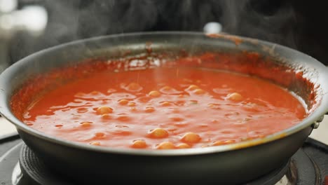 boiling tomato sauce on a frying pan close-up. cooking tomato sauce or soup. traditional italian mexican asian dish. high quality studio shot for cafe, restaurant close up. marinara sauce for italian pasta