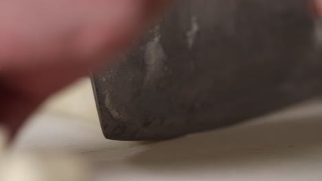 extreme close up shot of a chef slicing a roll of dough for dumplings with a large kitchen knife