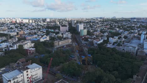 a breathtaking aerial video captures chennai city bathed in the golden hues of sunset. from a bird's-eye view, the city's sprawling urban landscape unfolds, with its intricate network of roads